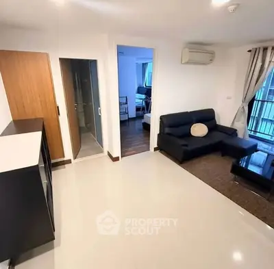 Modern living room with sleek black sofa and air conditioning, featuring a view into adjacent rooms.