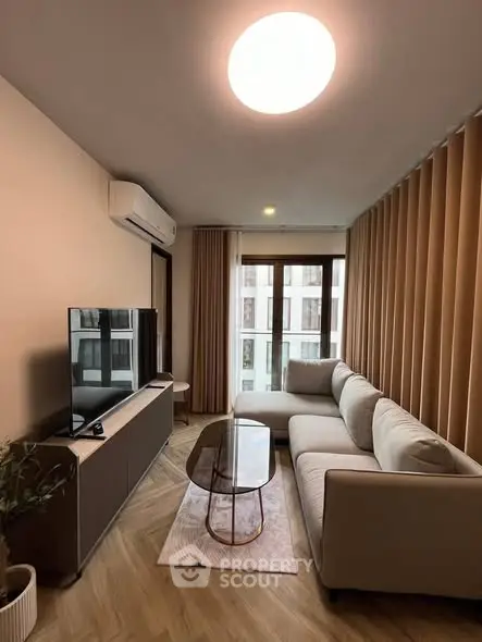 Modern living room with sleek furniture and large window offering natural light.