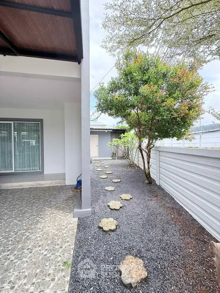 Charming outdoor pathway with stepping stones leading to a modern home entrance, surrounded by lush greenery.