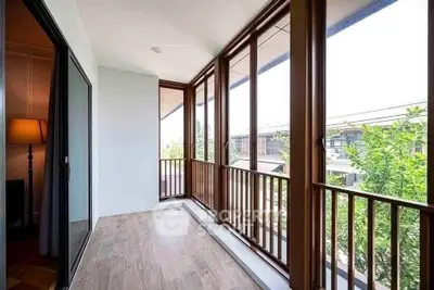 Spacious balcony with wooden flooring and large windows offering a serene view.