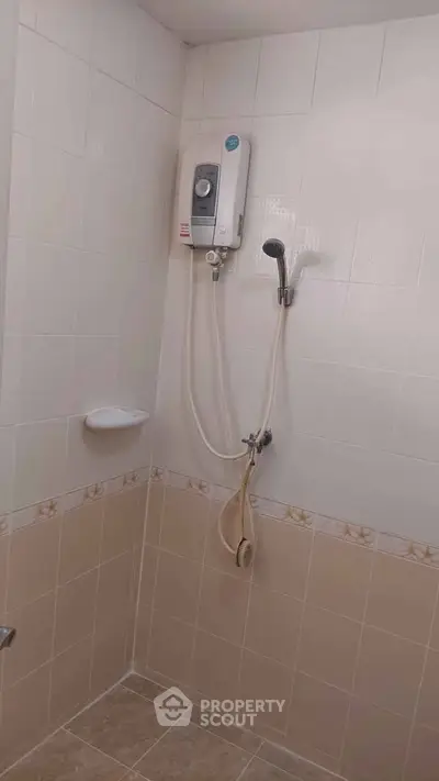 Compact bathroom with shower unit and tiled walls, ideal for efficient space use.