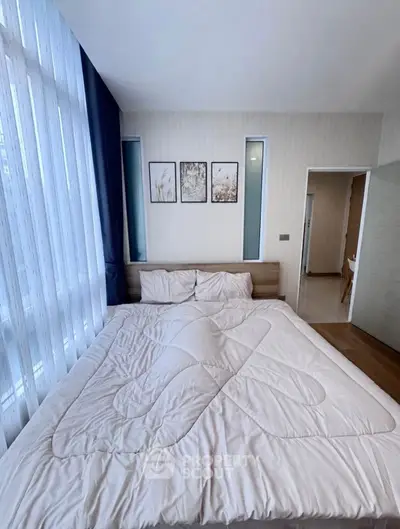 Spacious bedroom with large windows and modern decor, perfect for relaxation.