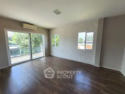 Spacious empty room with wooden flooring and balcony view, ideal for customization.