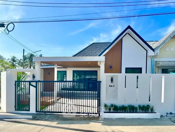 Modern single-story house with gated entrance and sleek design in a sunny neighborhood.