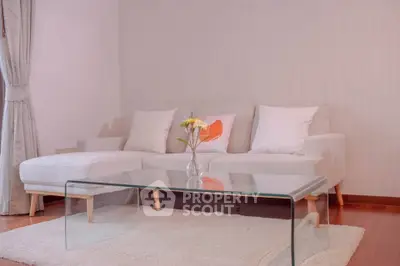 Elegant living room with modern glass coffee table and cozy white sofa.