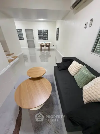 Modern living room with sleek furniture and minimalist design, featuring a cozy sofa and stylish coffee tables.