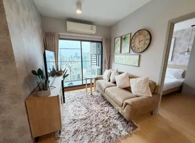 Modern living room with cozy sofa, stylish decor, and city view balcony in high-rise apartment.