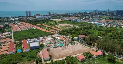 Aerial view of a vibrant coastal cityscape with residential and commercial buildings, lush greenery, and ocean views.