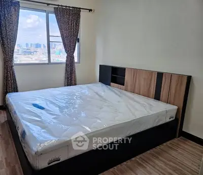 Spacious bedroom with large window offering city view and modern bed frame.