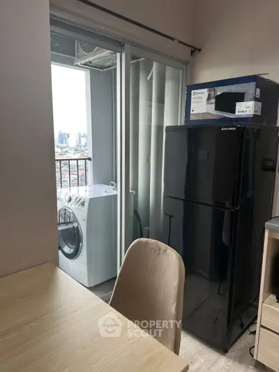 Modern apartment with balcony, washing machine, and sleek black fridge.