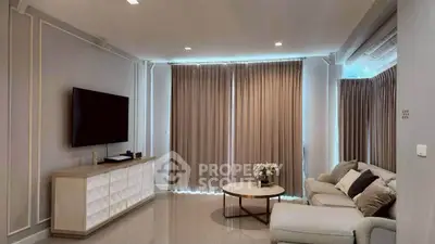 Elegant living room with modern decor, large TV, and cozy seating area, perfect for relaxation and entertainment.