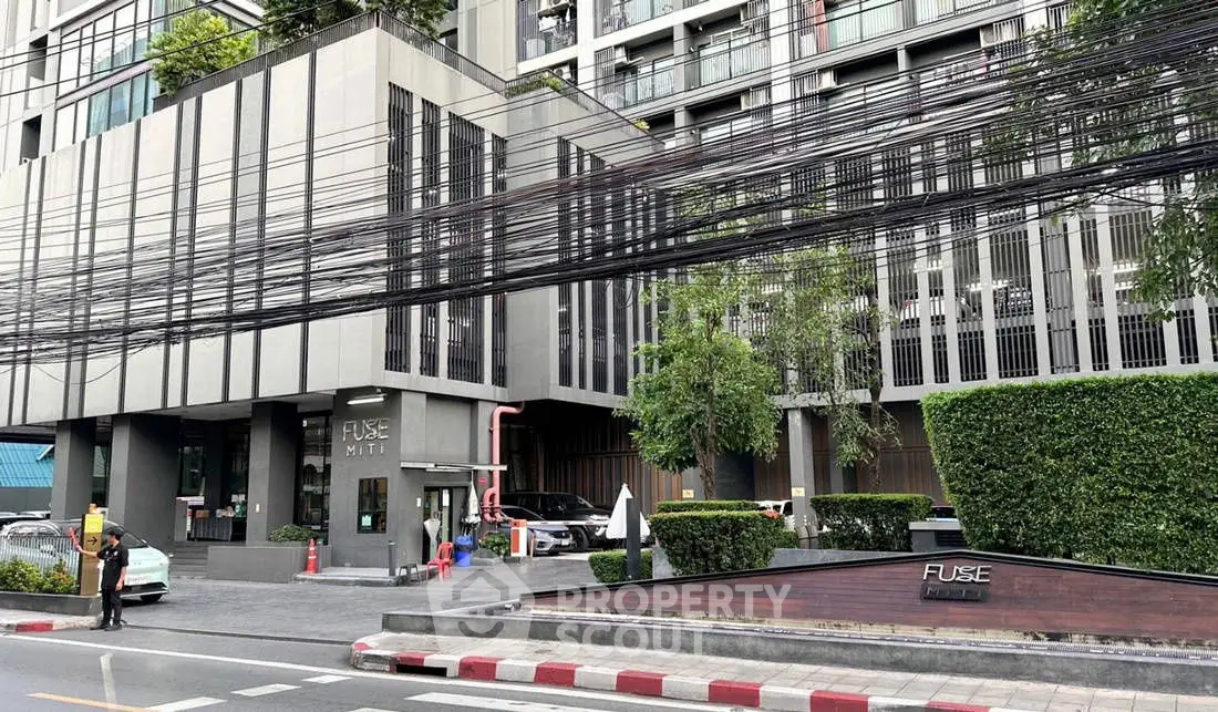 Modern urban building exterior with lush greenery and street view.