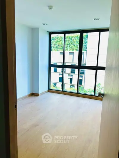 Bright empty room with large windows and wooden flooring, ideal for customization.