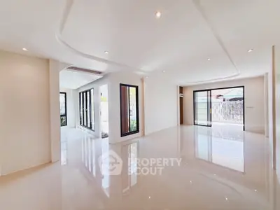 Spacious modern living room with large windows and glossy floors, perfect for natural light and open living.