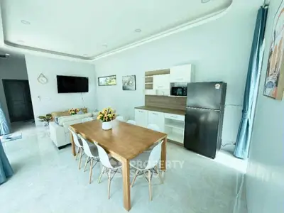 Spacious modern living room with open kitchen and dining area, featuring sleek furniture and bright decor.