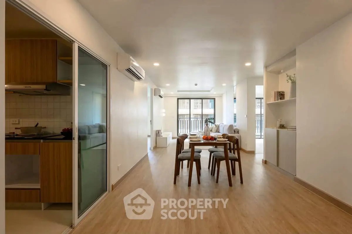 Spacious modern living room with open layout and elegant dining area, featuring wooden flooring and ample natural light.