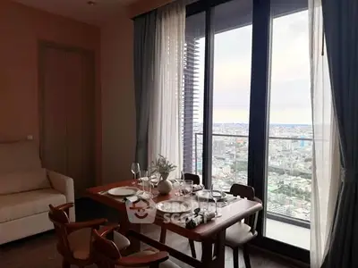 Elegant dining area with city view, featuring a wooden table set for four, adjacent to a large window and balcony.