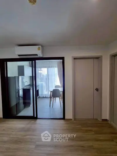 Modern apartment interior with open layout and balcony view, featuring sleek kitchen and dining area.