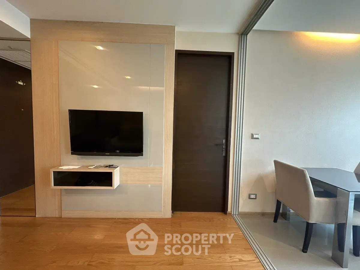 Modern living room with wall-mounted TV and dining area in stylish apartment