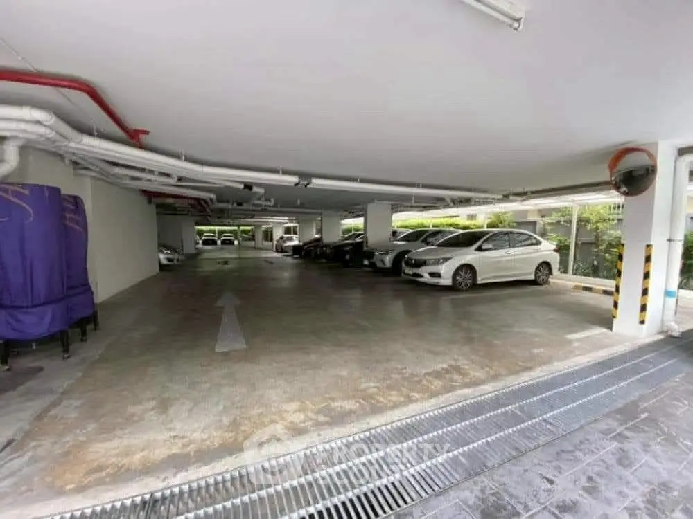 Spacious underground parking area with multiple parked cars and clear directional signage.