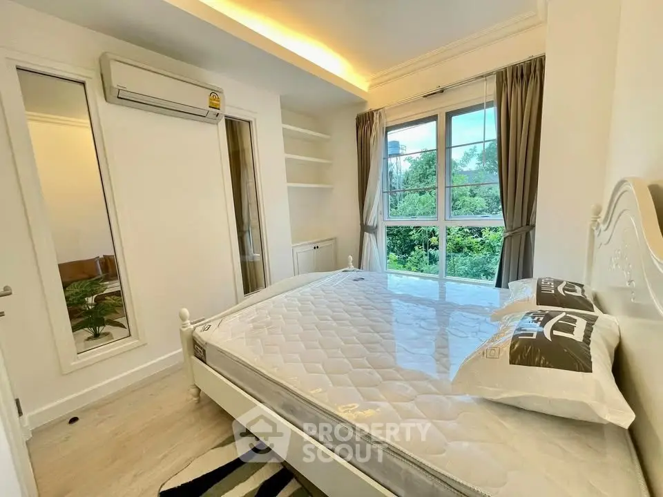 Bright bedroom with large window and modern decor, featuring a comfortable bed and air conditioning.