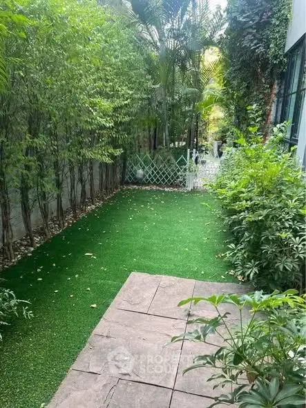 Charming garden with lush greenery and paved pathway, perfect for relaxation and outdoor activities.