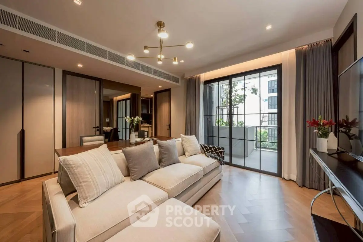 Luxurious living room with modern decor and large windows opening to a balcony with city views.