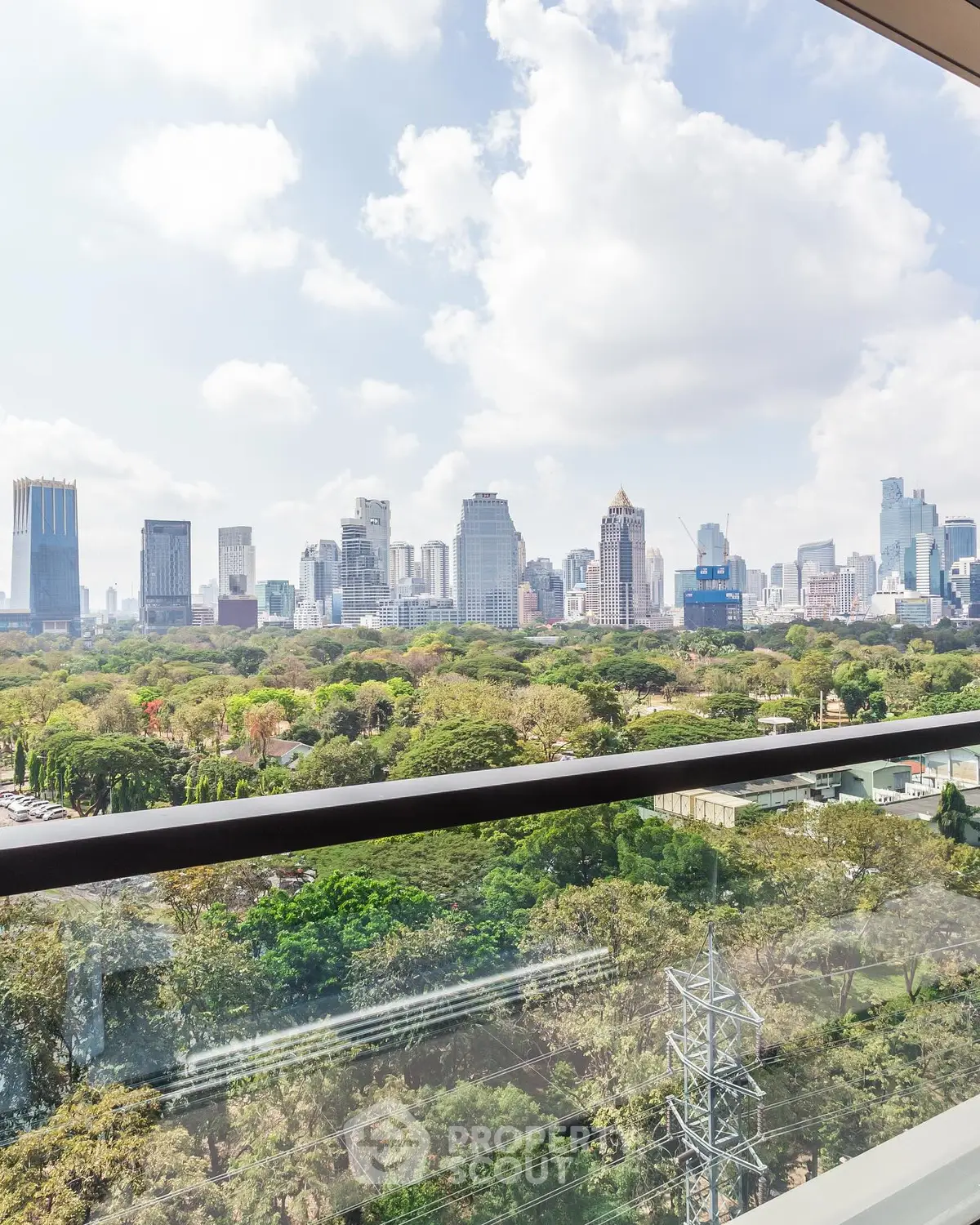 Stunning cityscape view from a high-rise balcony overlooking lush greenery and skyline.