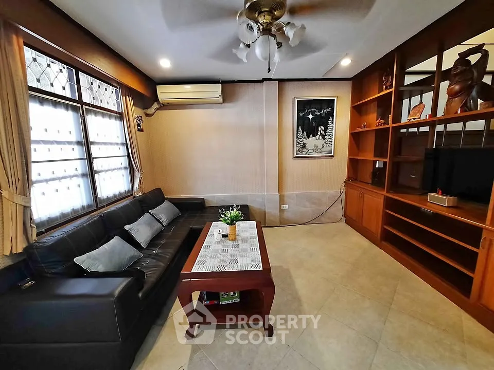 Spacious living room with elegant decor and ample natural light, featuring a comfortable sofa and stylish shelving.