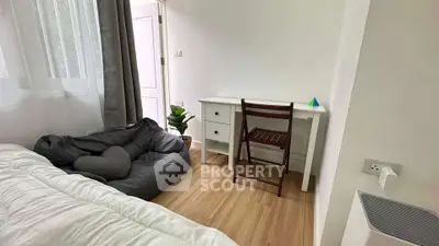 Cozy bedroom with study desk and bean bag, perfect for relaxation and work.