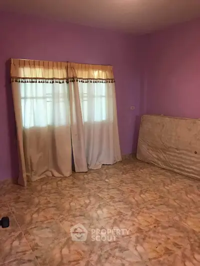 Spacious empty room with purple walls and tiled floor, featuring large windows with curtains.