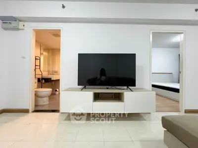 Modern living room with sleek TV unit, open bathroom view, and adjacent bedroom.