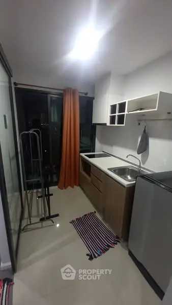 Modern compact kitchen with sleek design and stainless steel appliances in urban apartment.