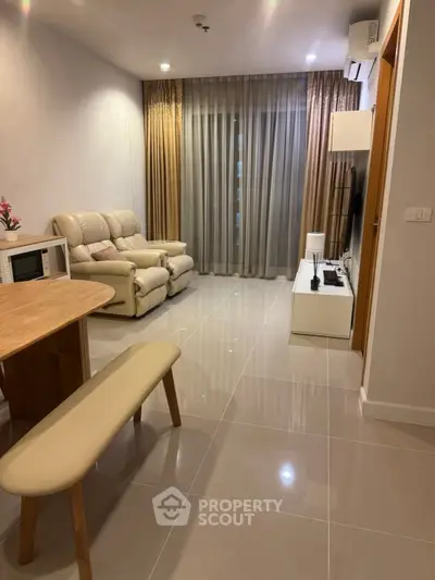 Modern living room with sleek furniture and large window drapes.