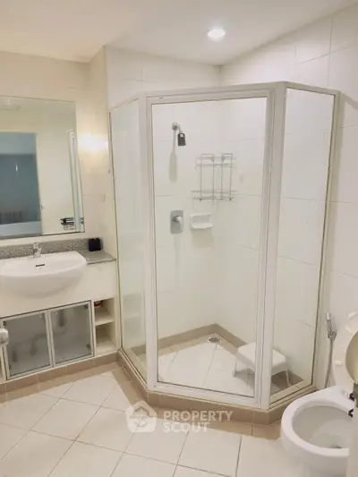 Modern bathroom with glass shower enclosure and sleek vanity in a contemporary apartment.