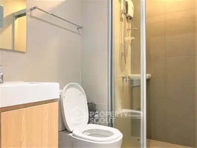 Modern bathroom with glass shower and sleek fixtures in contemporary apartment.