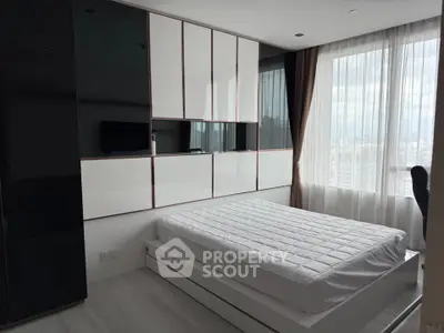 Modern bedroom with sleek built-in storage and large window offering city views.