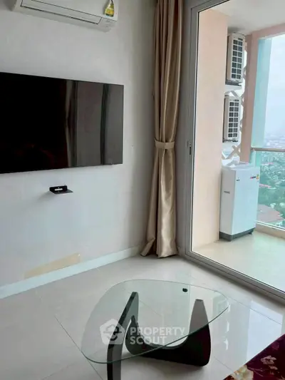 Modern living room with glass table and balcony view in high-rise apartment.