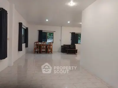 Spacious open-plan living room with dining area and tiled flooring.