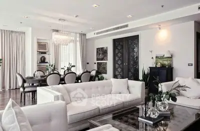 Luxurious open-plan living room with elegant decor and dining area, featuring plush sofas and a chic chandelier.