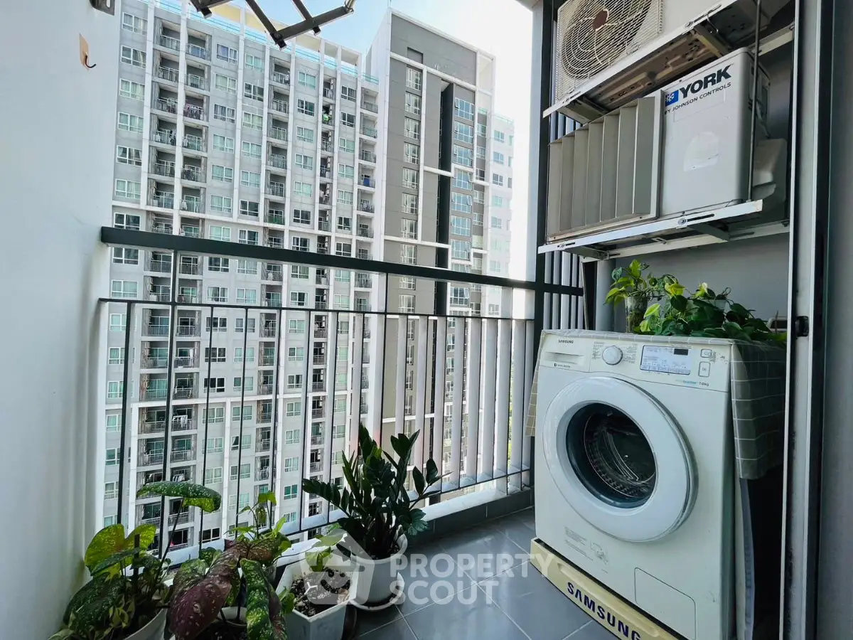 Modern apartment balcony with washing machine and plants, overlooking cityscape.