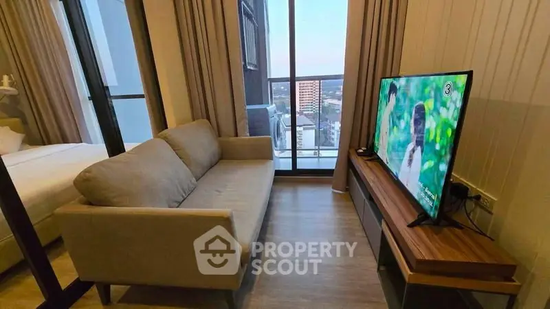 Modern living room with cozy sofa and large TV, featuring a stunning city view from the balcony.