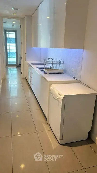 Sleek modern kitchen with white cabinetry and integrated appliances in a stylish apartment.