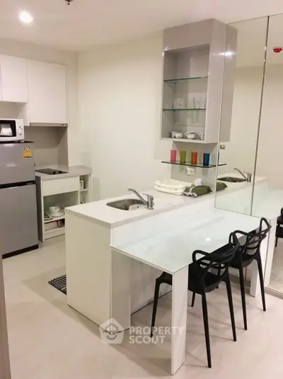 Modern kitchen with sleek design, featuring a compact fridge, microwave, and stylish dining area.