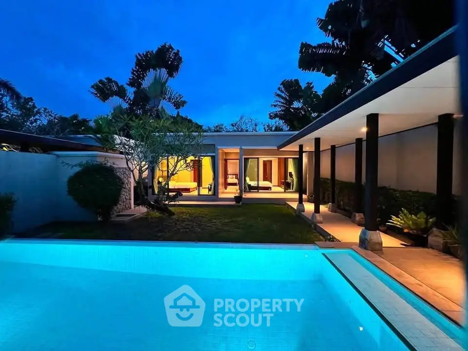 Luxurious villa with illuminated pool and modern architecture at dusk, surrounded by lush greenery.