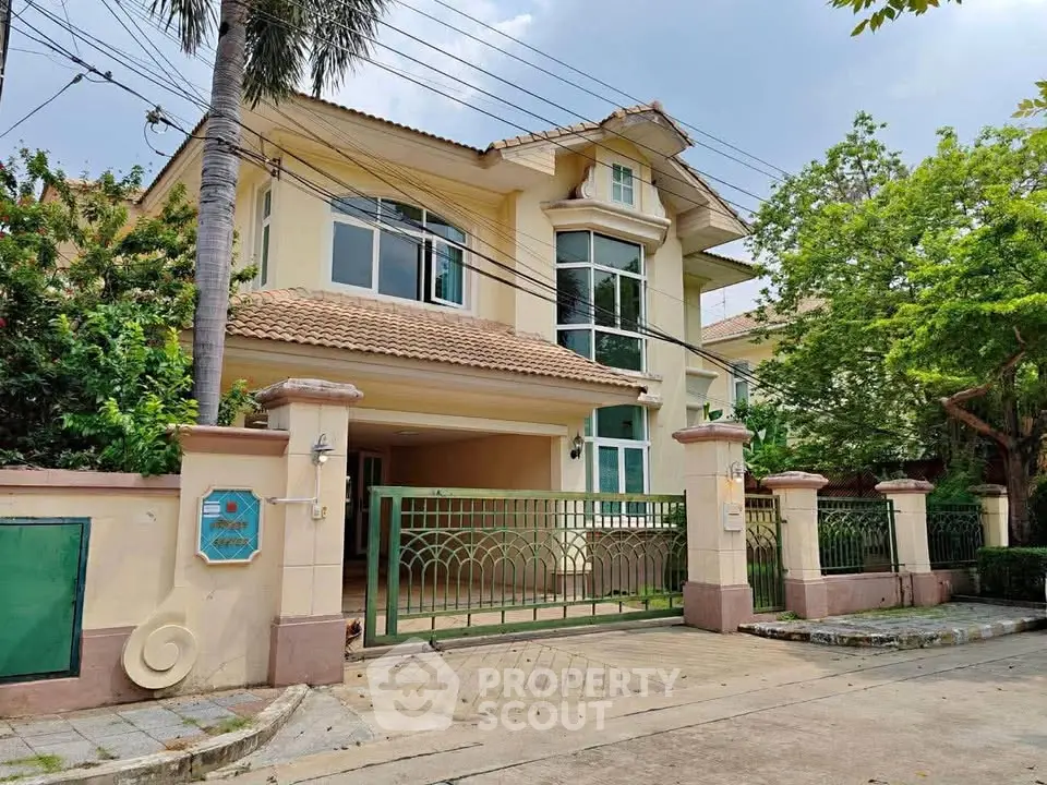 Charming two-story house with gated entrance and lush greenery, perfect for family living.