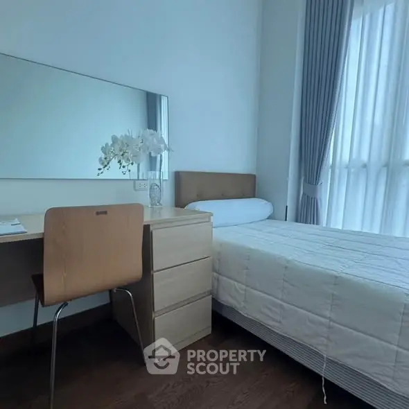Cozy bedroom with natural light, wooden flooring, and modern furniture.