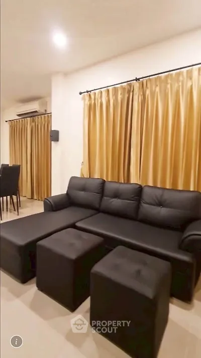 Spacious living room with elegant black sofa and golden curtains, perfect for modern living.