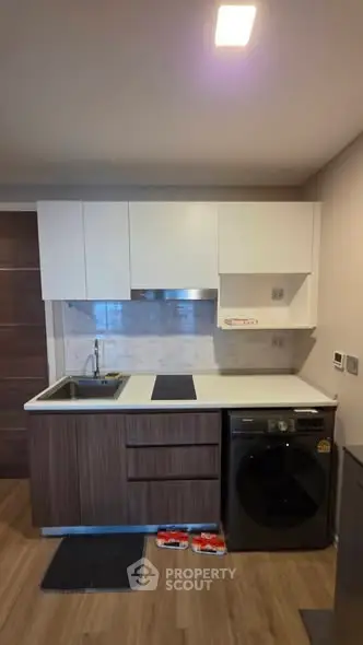 Modern compact kitchen with sleek cabinetry and integrated washing machine