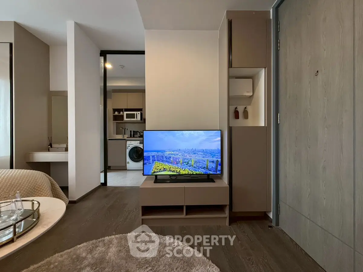 Modern living room with TV, cozy seating, and open kitchen layout.